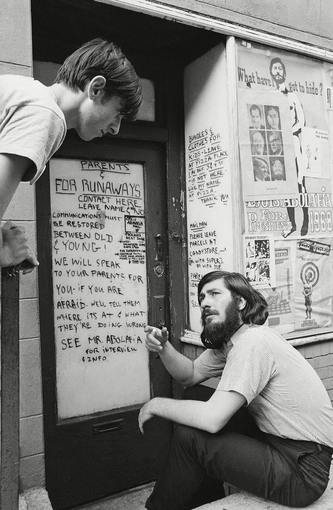 "Louis Abolafia speaks to a young man outside of the clearing house he operates for runaways in the East Village on . Abolafia offers to act as a go-between for estranged parents and children. 1968."